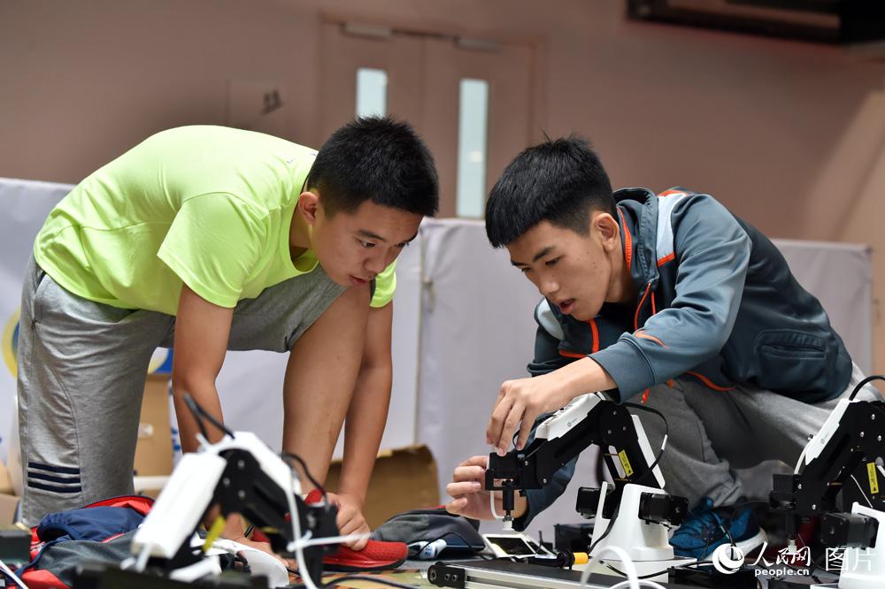 8月23日，参赛选手正在调试机器手臂，准备比赛。（人民网记者 翁奇羽摄）