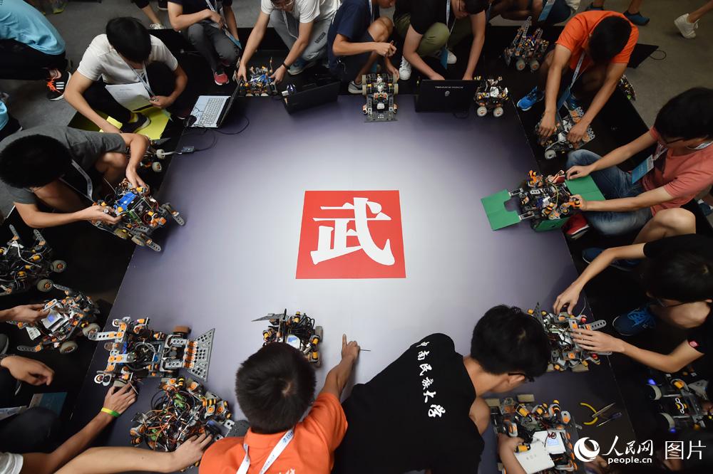 8月23日，参赛选手正在调试格斗机器人，准备比赛。（人民网记者 翁奇羽摄）